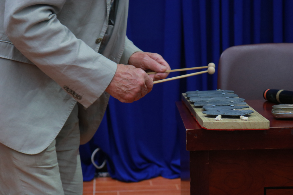 Mike Adcock chơi đàn đá để chỉ cái “hồn” của âm thanh do con người làm ra cho khán giả - Ảnh: Phạm Trí