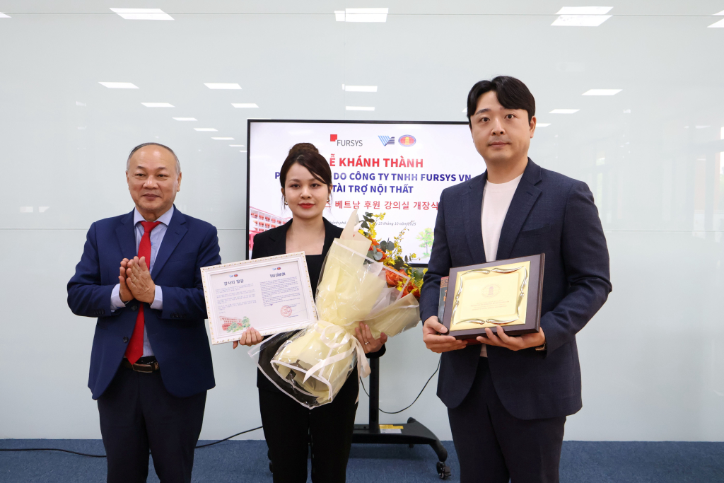 TS. Phan Thanh Định trao lẵng hoa tươi thắm và quà lưu niệm cho ông Lee Jaehyuk và bà Nguyễn Thúy Nhi, thay lời cảm ơn từ Nhà trường - Ảnh: TIẾN ANH