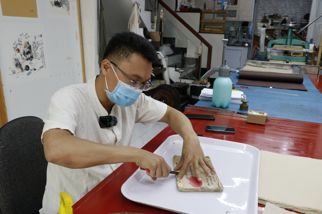 “Bác sĩ sách” Bùi Tiến Phúc đang tiến hành sửa chữa một tài liệu cổ - Ảnh: Tuyết Hồng